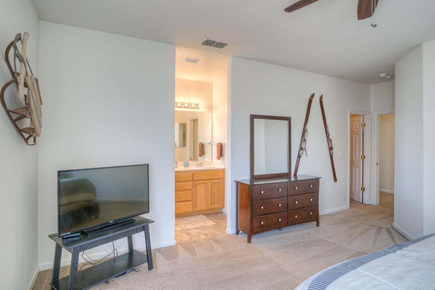 Bedroom with a dark wood dresser, wall-mounted vintage skis, and an adjoining bathroom vanity.
