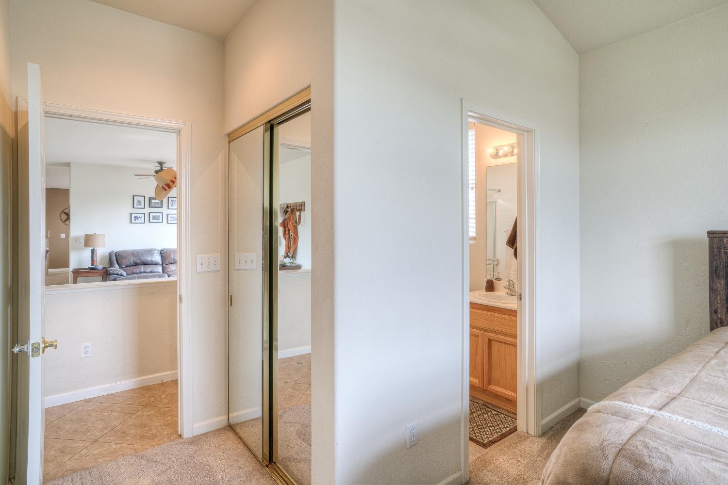 Bedroom with mirrored closet doors and an adjoining bathroom with a wood vanity.