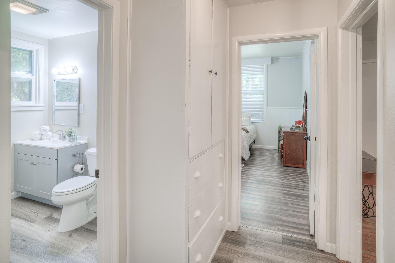 Hallway with built-in cabinets, gray plank flooring, and views into a bathroom and bedroom.