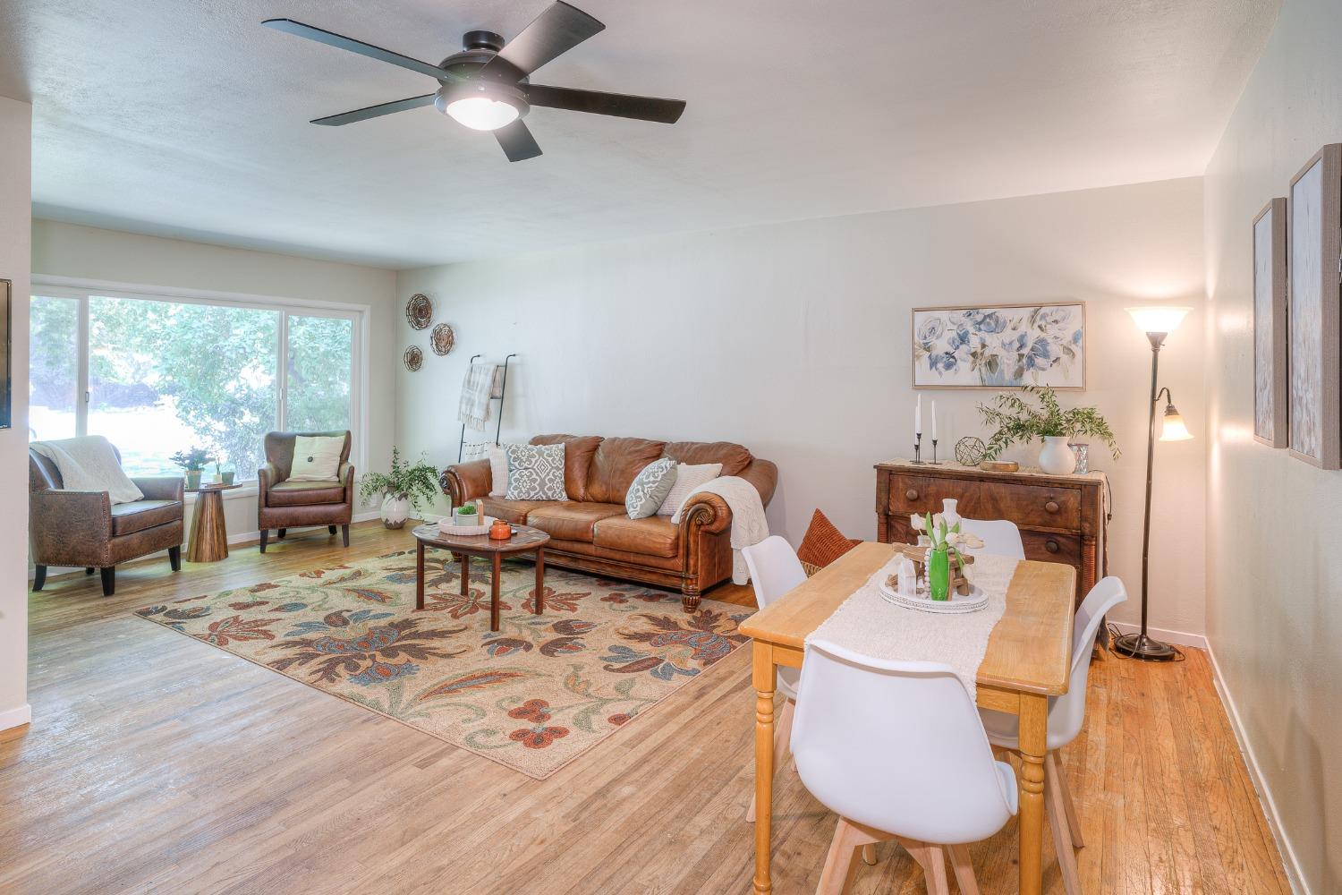 Living and dining room with brown leather seating, a patterned rug, and a wooden dining table.