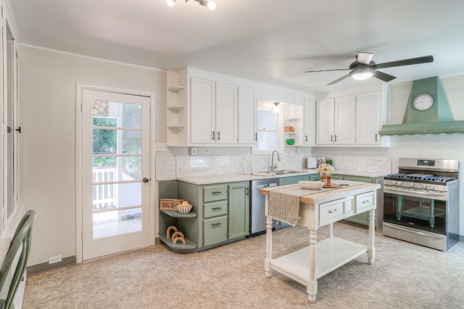 Kitchen with sage-green lower cabinets, a central island, and stainless-steel range.