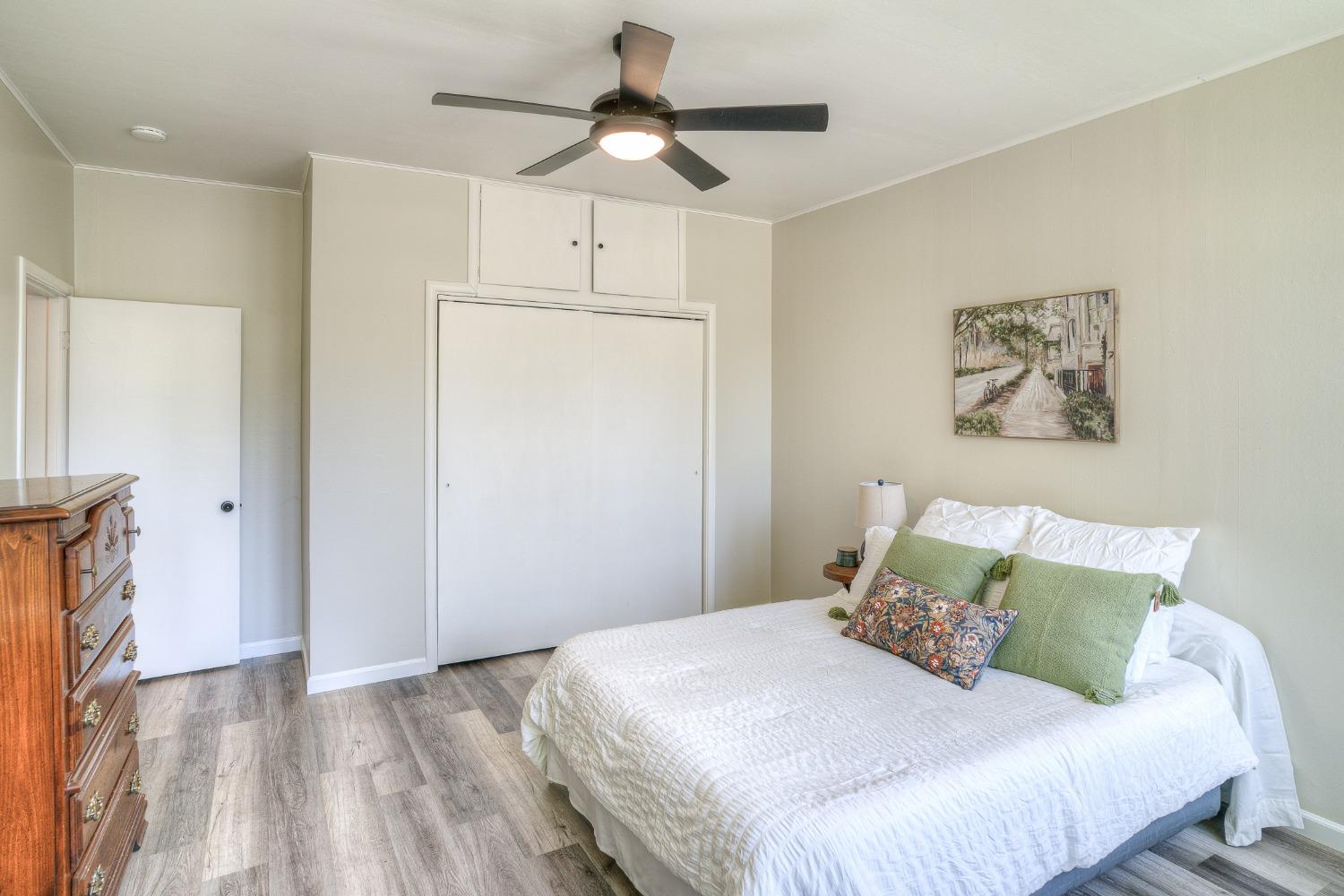 Bedroom with white bed, green accent pillows, and wide sliding closet doors.
