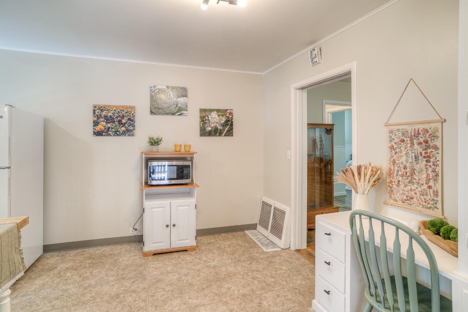 Kitchen with a microwave cabinet, floral wall art, and an adjoining room visible through the doorway.