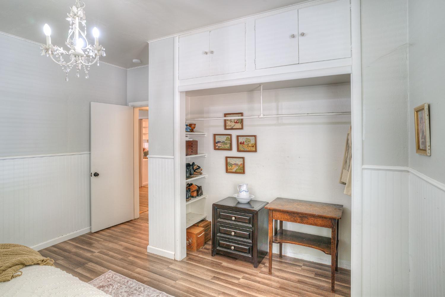 Bedroom with built-in wardrobe, dressing alcove, chandelier, and wood-look flooring.
