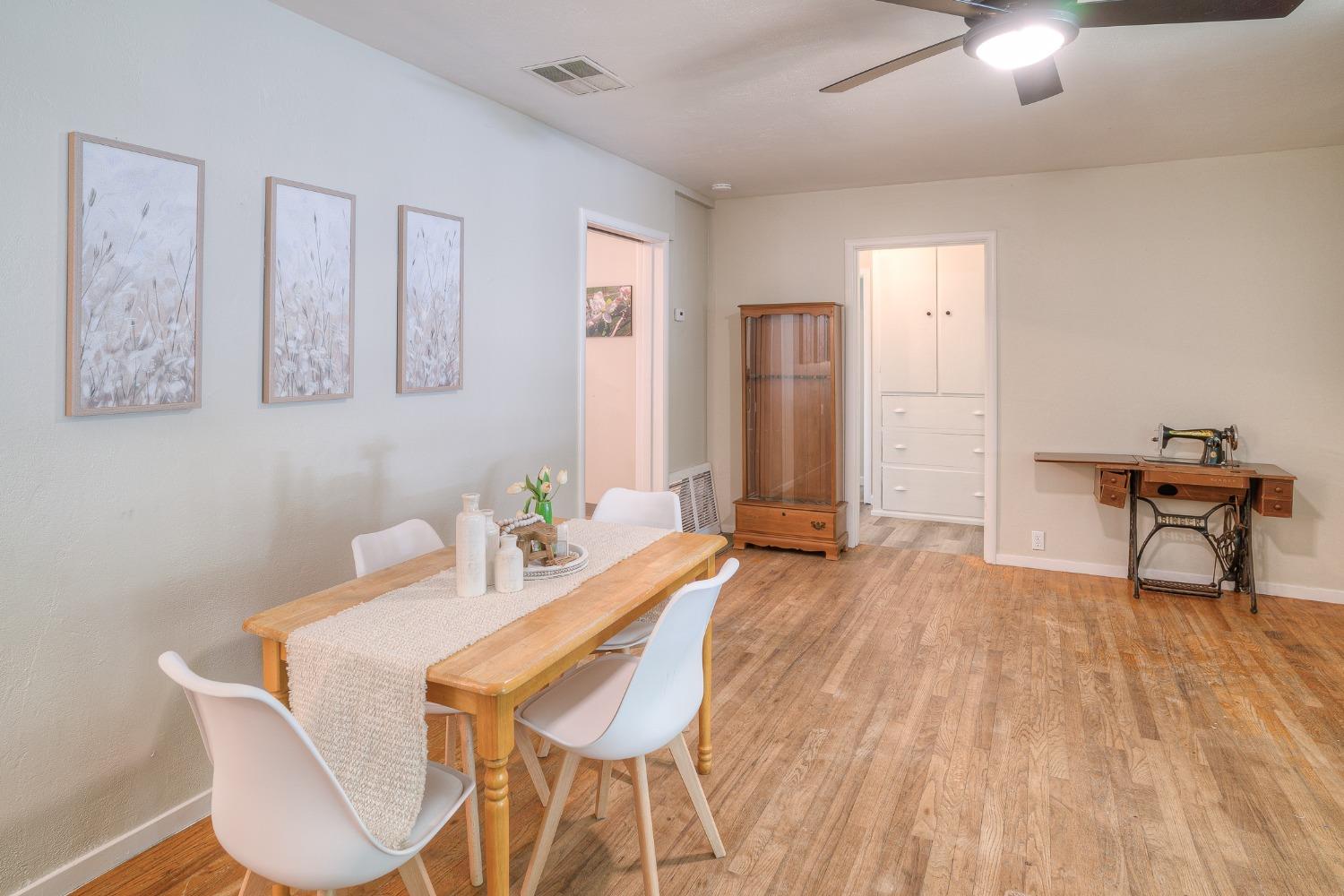 Dining room with a wooden table, white chairs, and a vintage sewing machine on a wooden floor.