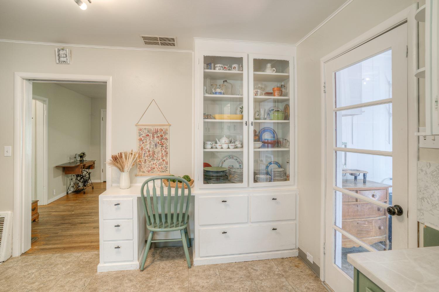 Kitchen with a glass-front dish cabinet and small desk nook beside a glass-paneled door.