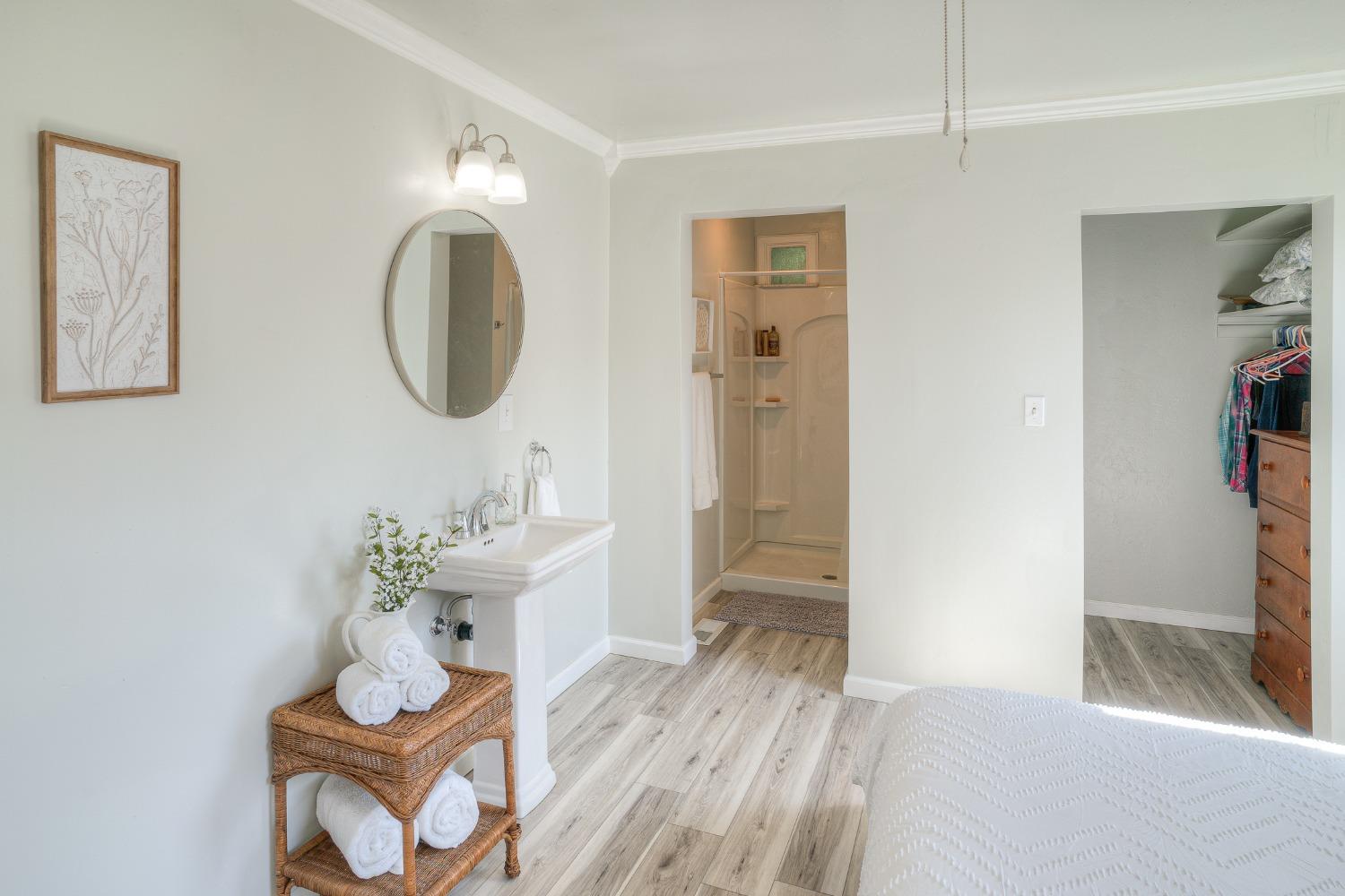 Bedroom with a pedestal sink, open shower doorway, and walk-in closet.