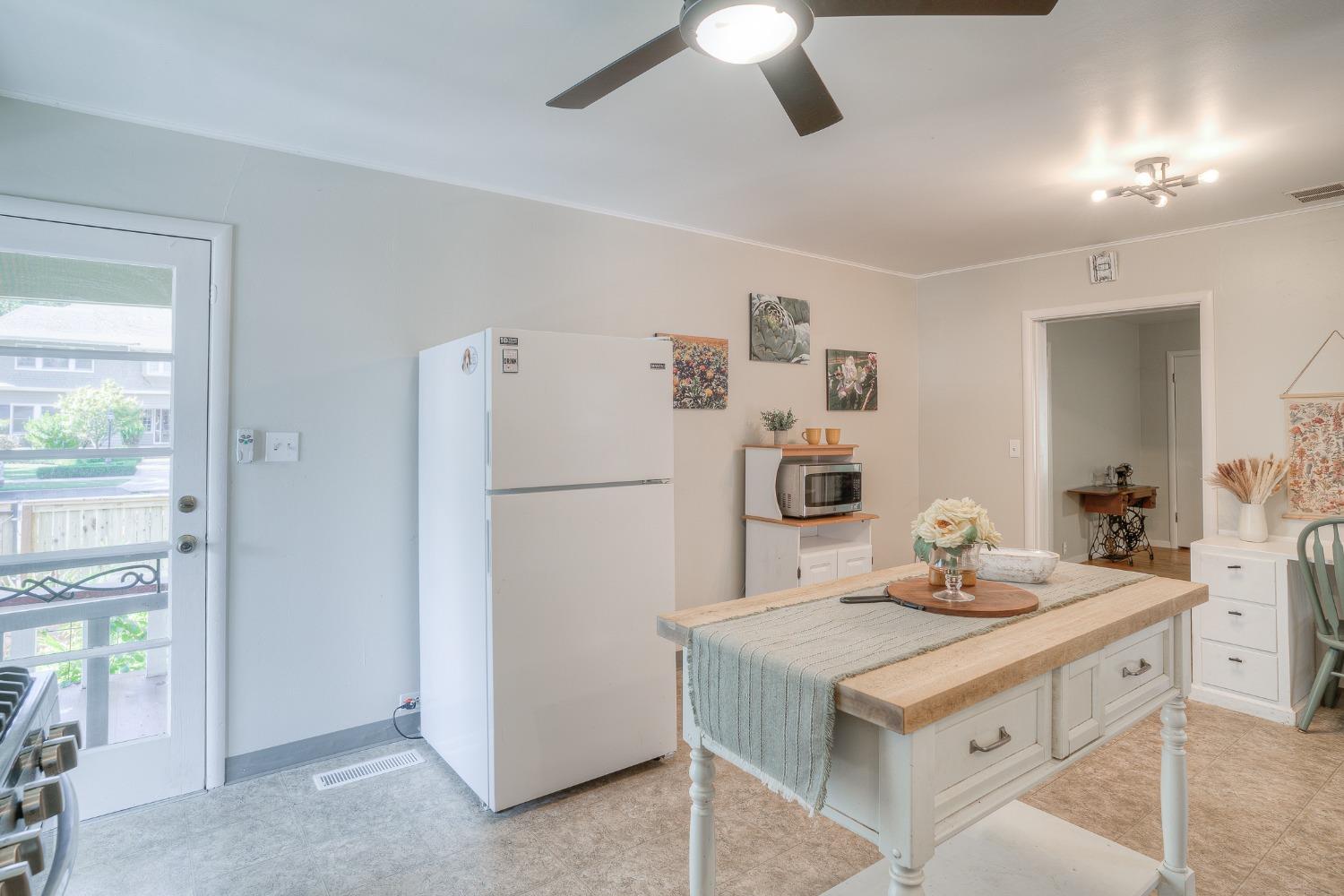 Bright kitchen with a wood-top island, white cabinetry, and a glass back door.