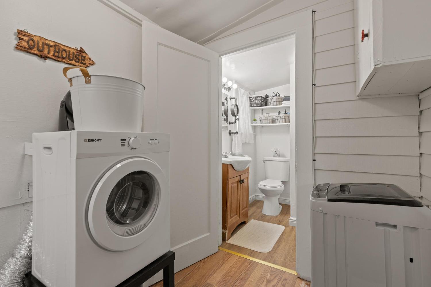 Laundry area with two washing machines beside an open doorway to a bathroom with a wood vanity.