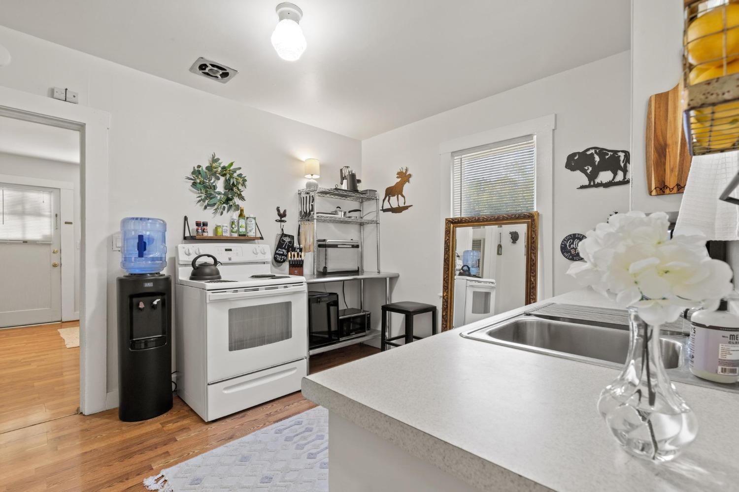 Kitchen with white stove, open metal shelving, and a sink set into the foreground countertop.