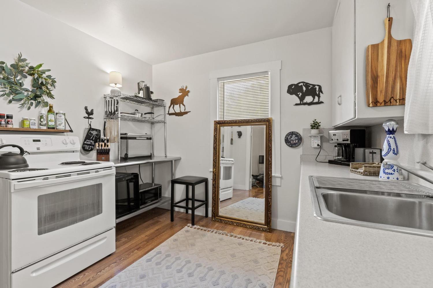 Kitchen with a white range, stainless sink, open shelving, and a large ornate mirror.