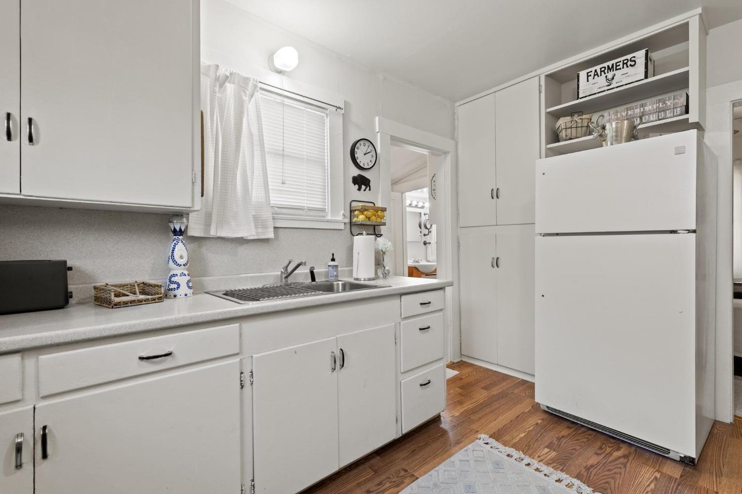 Kitchen with white cabinetry, a window over the sink, and a large white refrigerator.