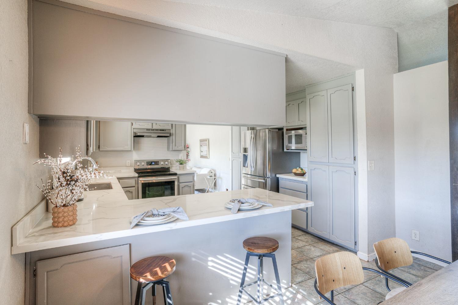 Kitchen with a large marble-look island, white cabinetry, and stainless steel appliances.