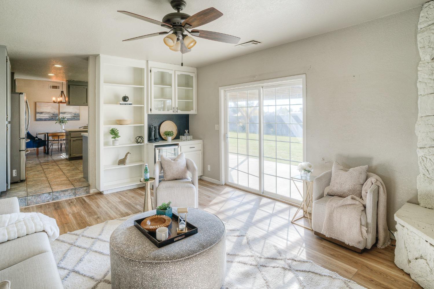 Staged living room with built-in shelving, sliding glass doors, and a view of the backyard.