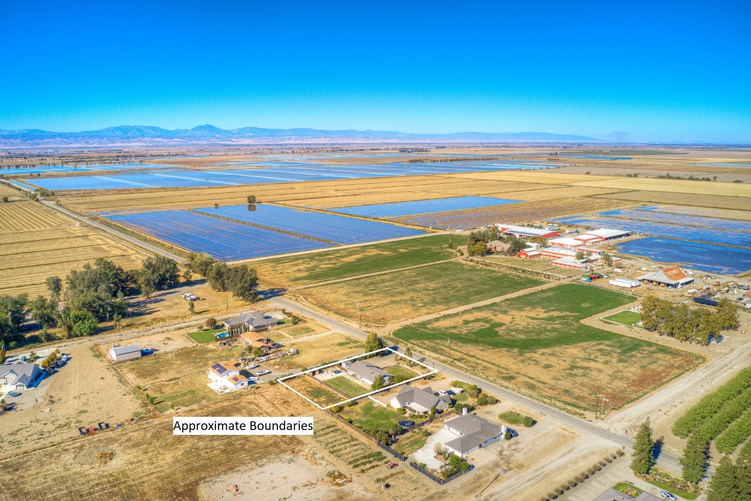 Aerial view of the outlined property amid farmland, with distant mountains beyond.