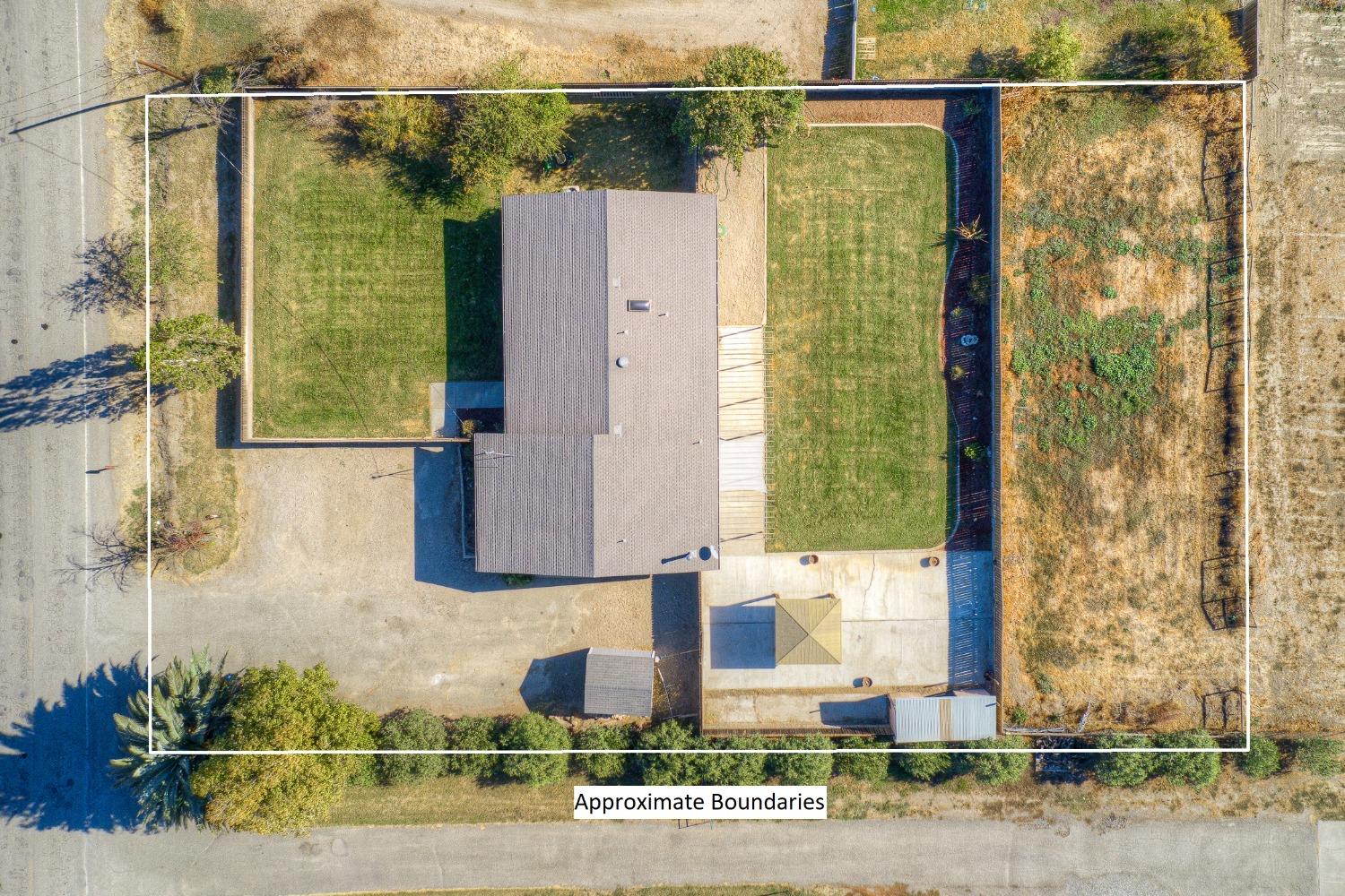 Aerial view of a house and lawns within white lines marking approximate property boundaries.