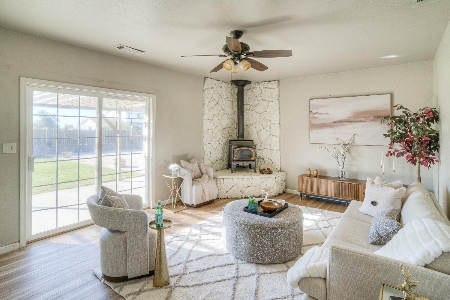 Living room with a stone fireplace and wood stove beside a large sliding glass door.