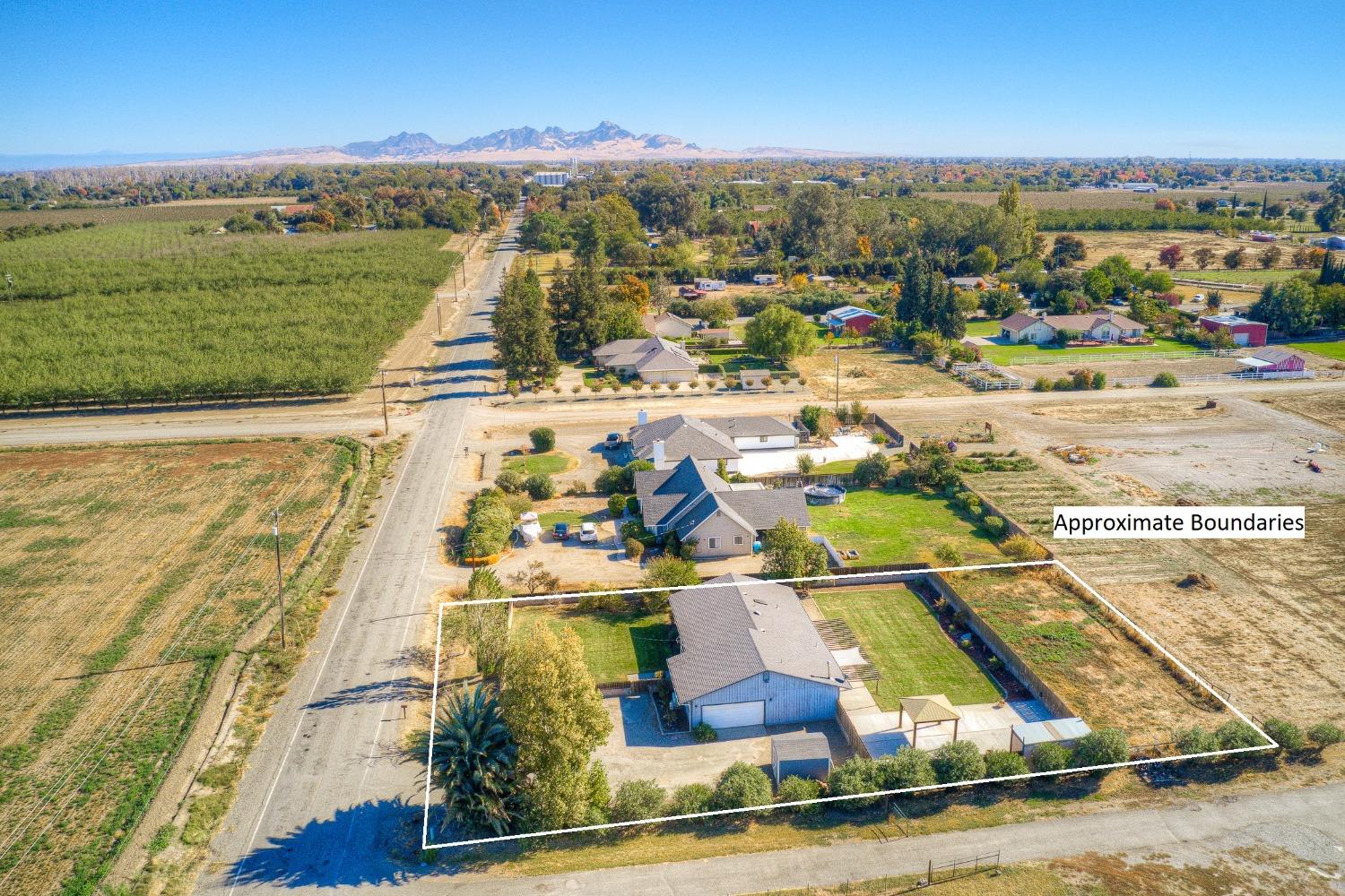 Aerial view of outlined property, neighboring farmland, and distant mountains.
