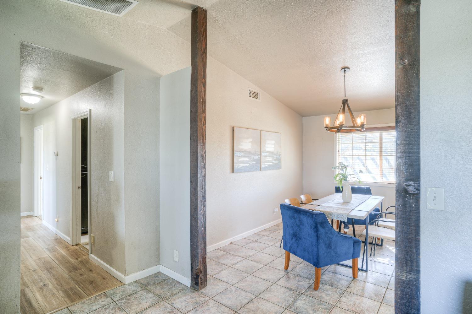 Dining area with a tiled floor, blue chairs, a table, and exposed wood posts.