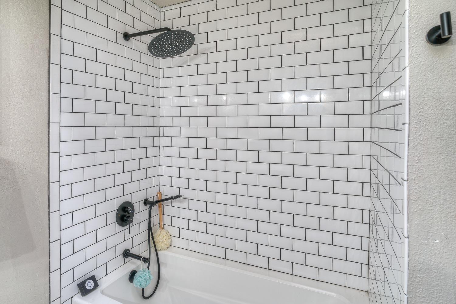 Bathroom tub and shower with white subway tile and matte black fixtures.