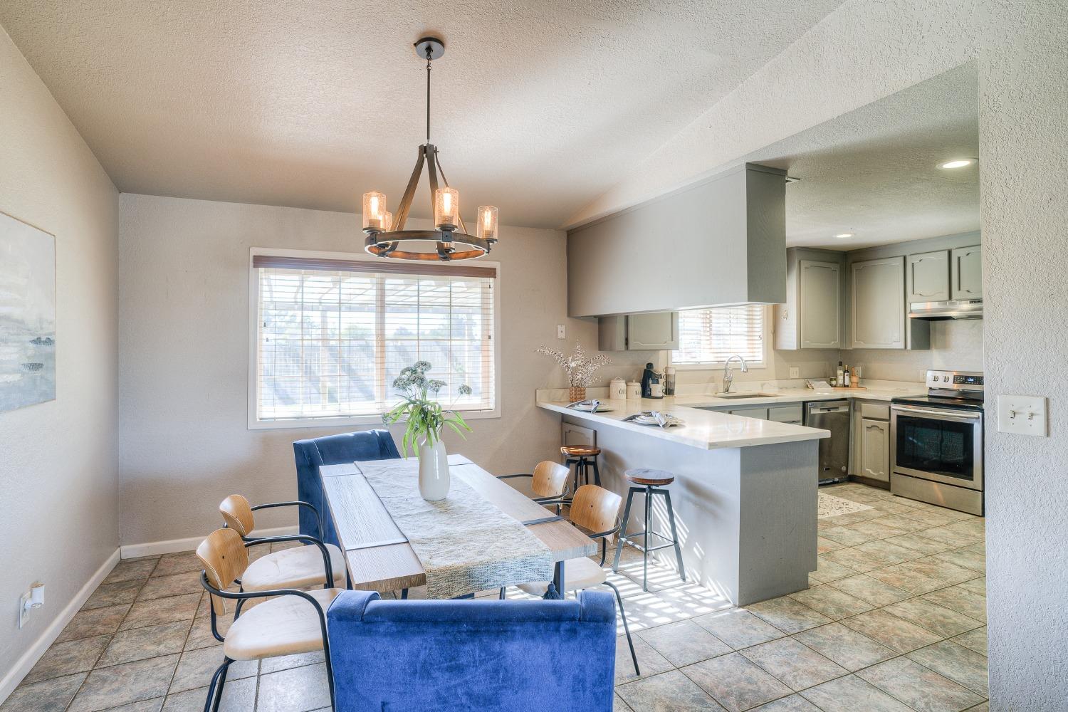 Open-plan dining area and kitchen with blue chairs, a breakfast bar, and stainless steel appliances.