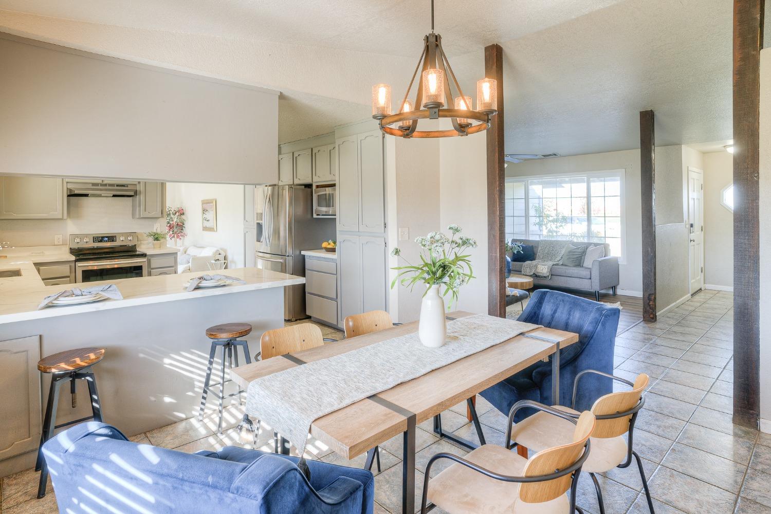 Open-plan kitchen and dining room with white cabinets, a long wood table, and blue seating.