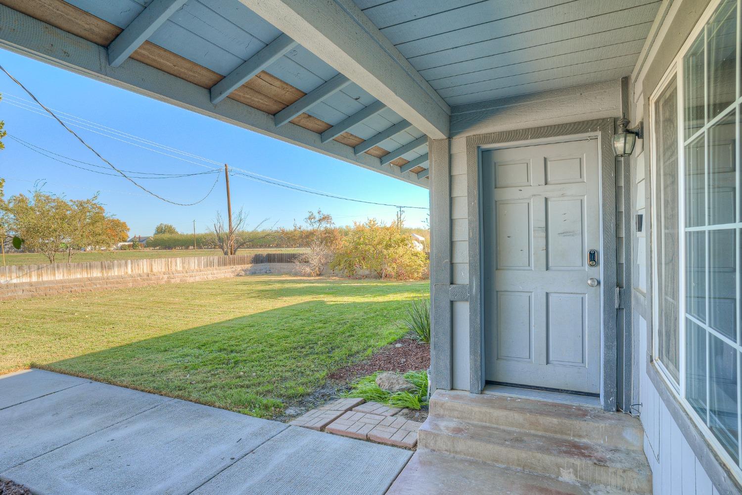 Covered front porch with a paneled entry door overlooking a broad lawn.