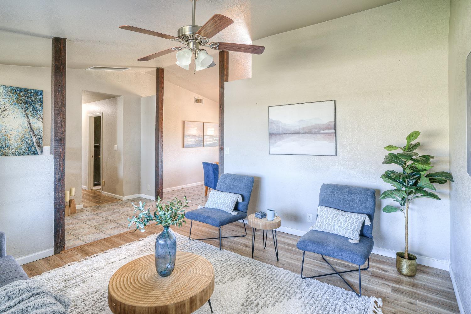 Staged living room with blue chairs, a round wood coffee table, and dark wood posts.
