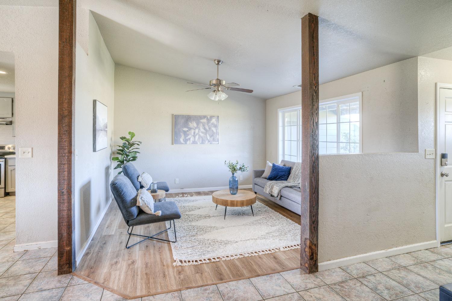 Staged living room with gray sofas, a round wood coffee table, and dark exposed wood posts.