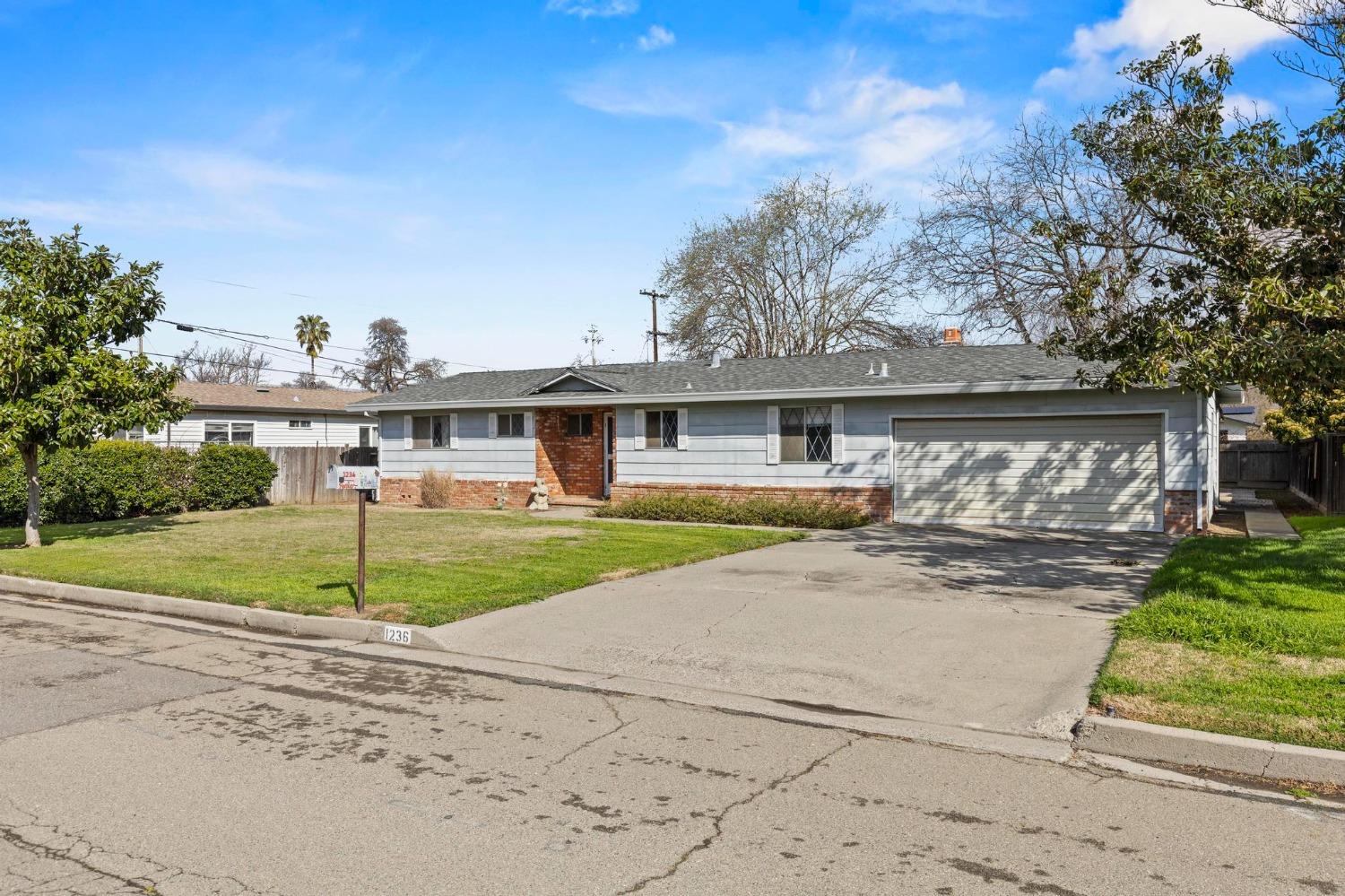 Single-story gray house with a brick entry, wide garage, and concrete driveway.