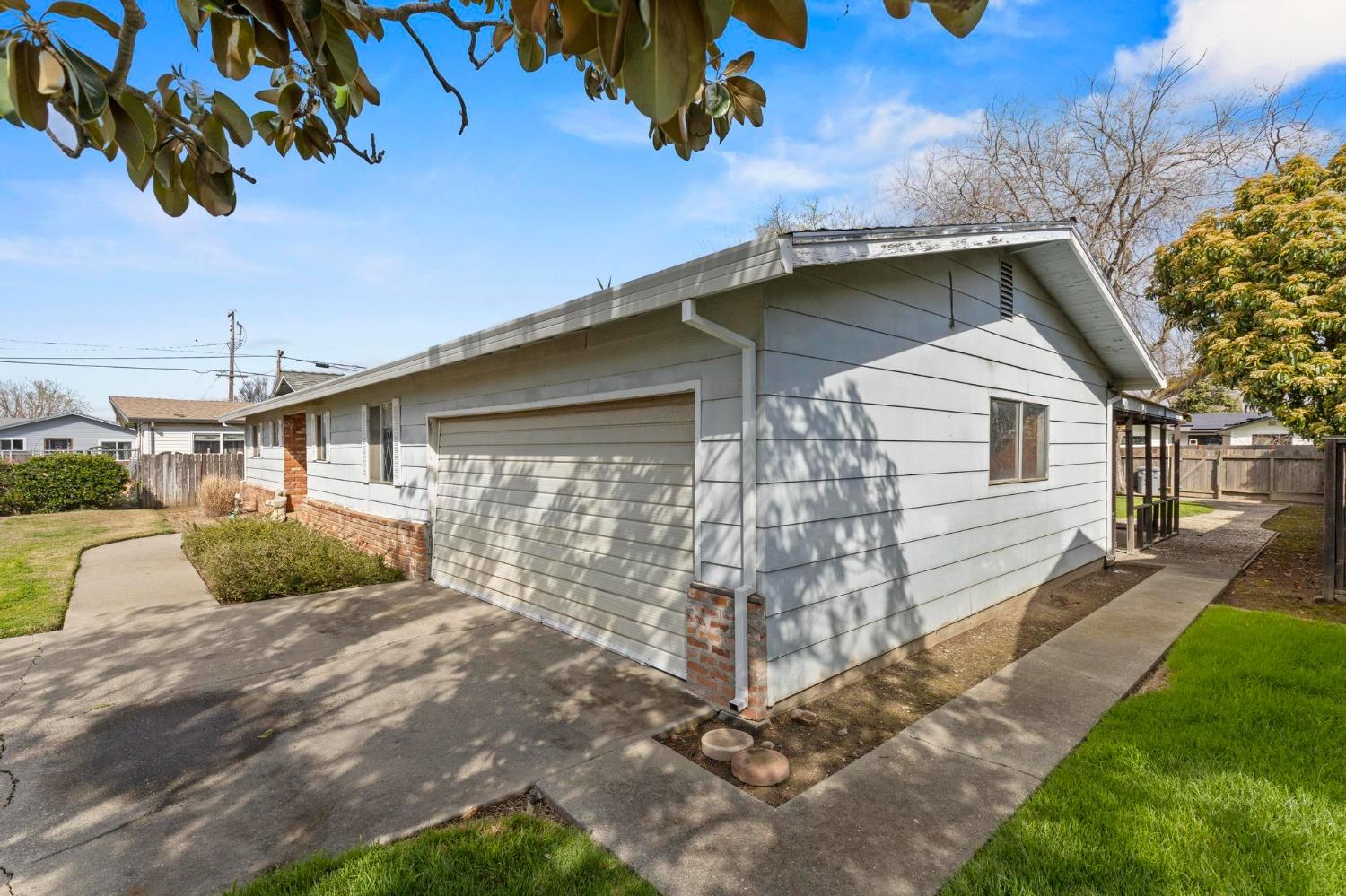 Gray single-story house with a wide garage, driveway, and walkways around the side.