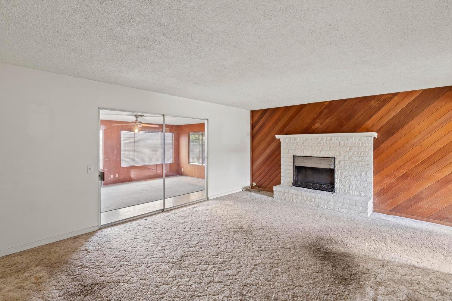 Unfurnished living room with a white brick fireplace and diagonal wood-paneled accent wall.