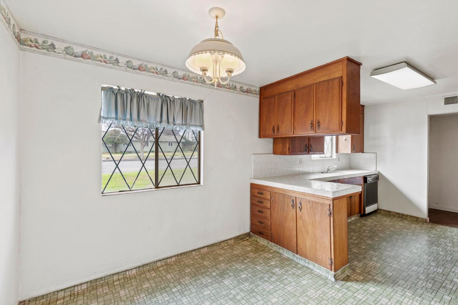 Kitchen with wood cabinets, a peninsula counter, and patterned tile flooring.