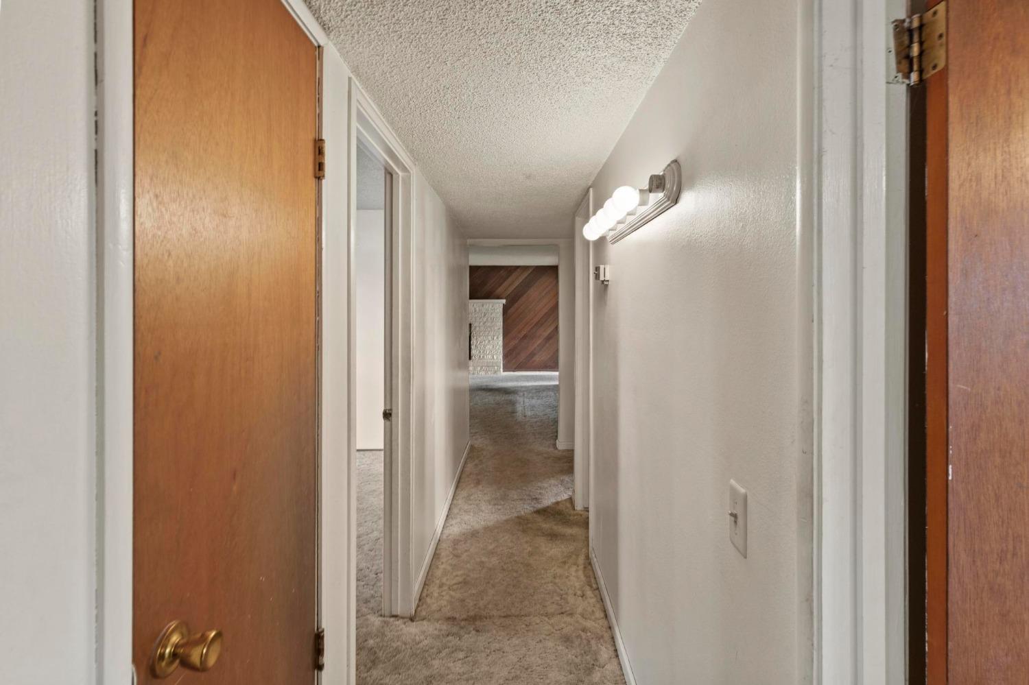Carpeted hallway with wood doors and a wall-mounted light fixture.