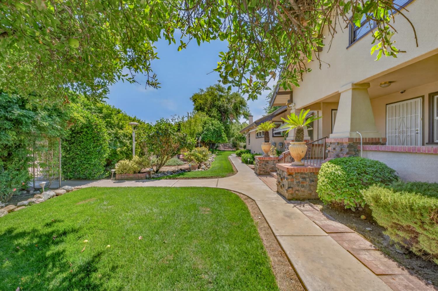 Two-story home beside a landscaped lawn, with a curving walkway and brick patio.