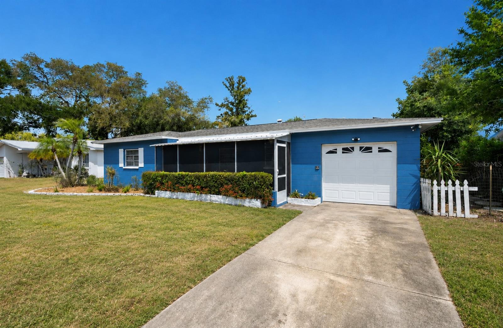 Blue single-story house with a screened porch, white garage door, and concrete driveway.