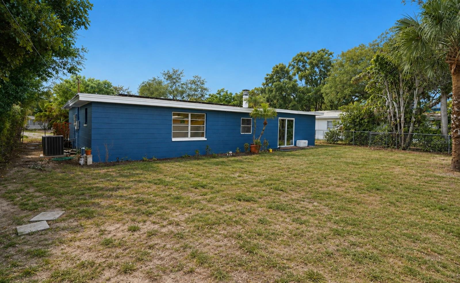 Rear of a blue single-story house with white trim, sliding glass door, and a broad lawn.