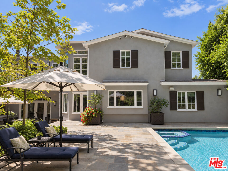 Two-story gray stucco home with a swimming pool and furnished stone patio.