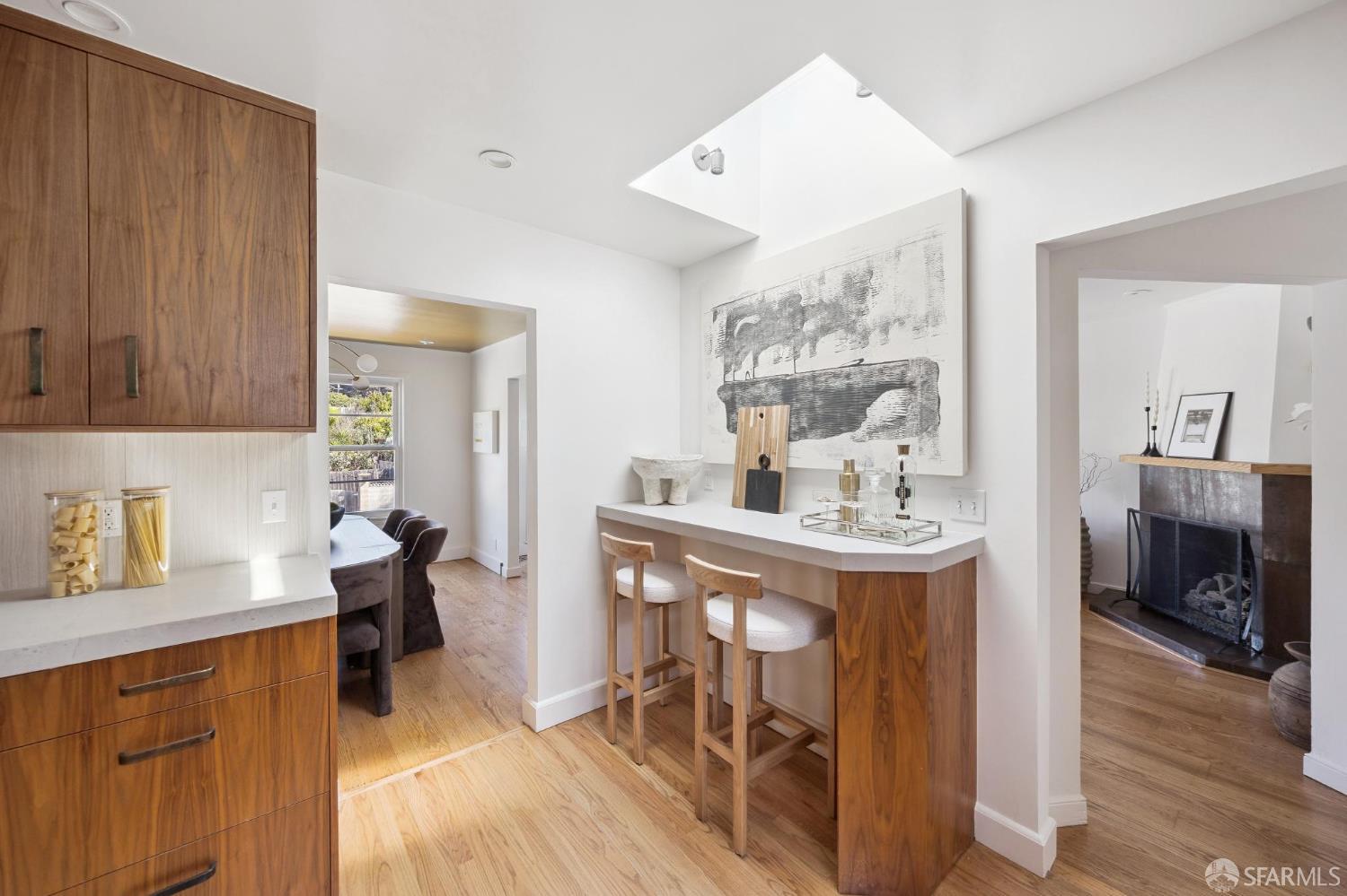 Kitchen with walnut cabinetry and a breakfast peninsula, opening to a dining nook and living room with fireplace.