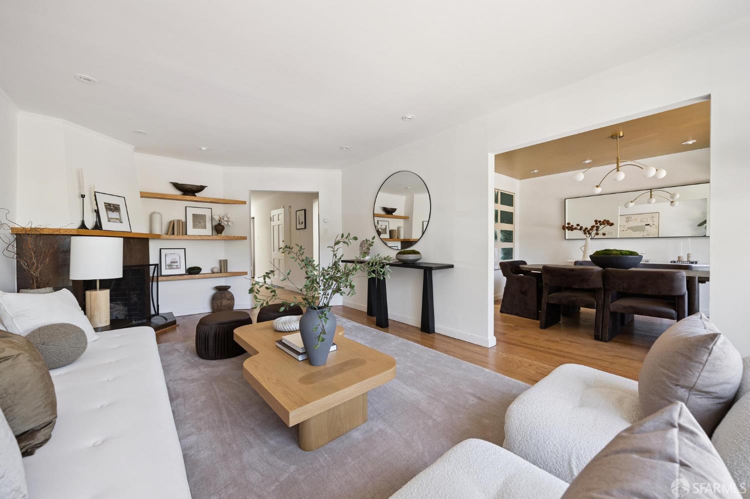 Staged living room with white sofas, floating fireplace shelves, and an adjoining dining area.