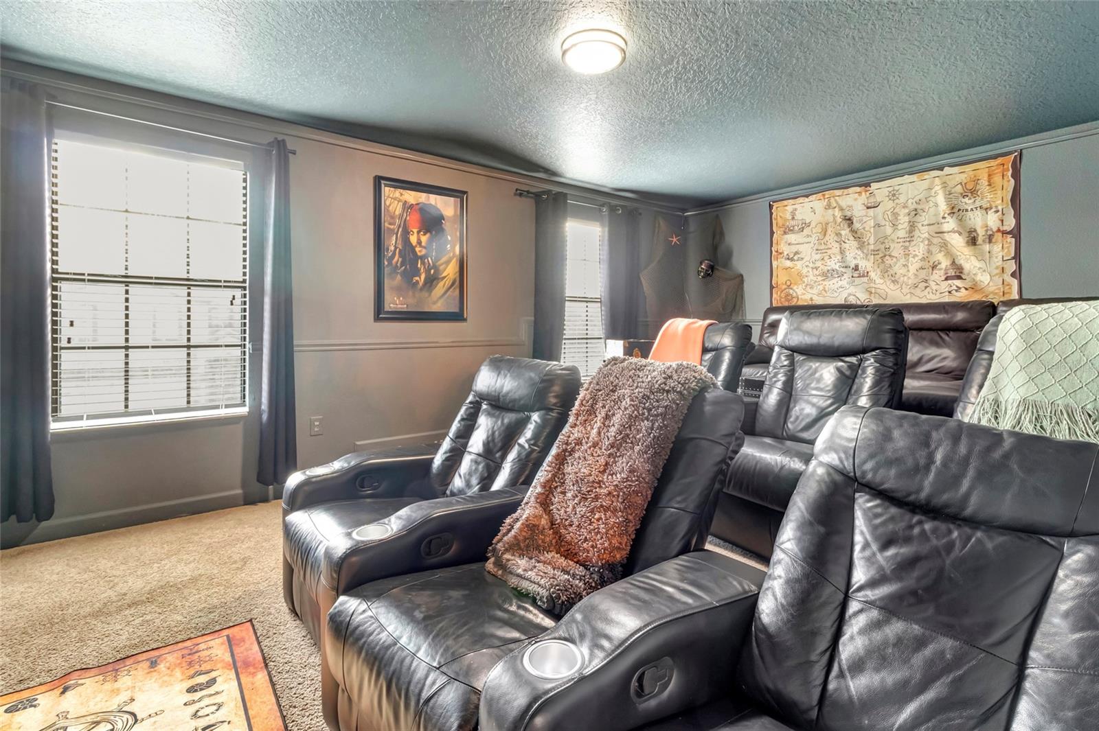 Furnished home theater with black leather recliners and a large pirate-themed map.