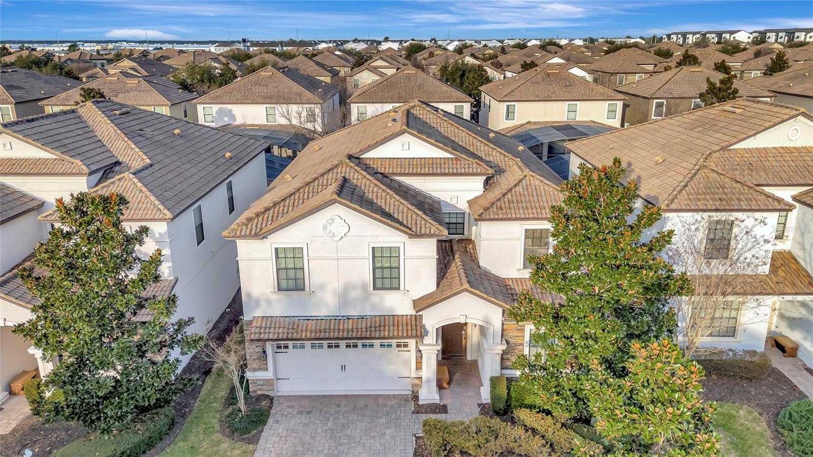 Two-story stucco home with a tiled roof, attached garage, and landscaped front yard.
