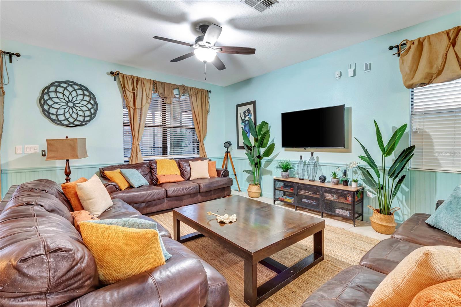 Furnished living room with leather sectional sofas, turquoise walls, and a wall-mounted television.