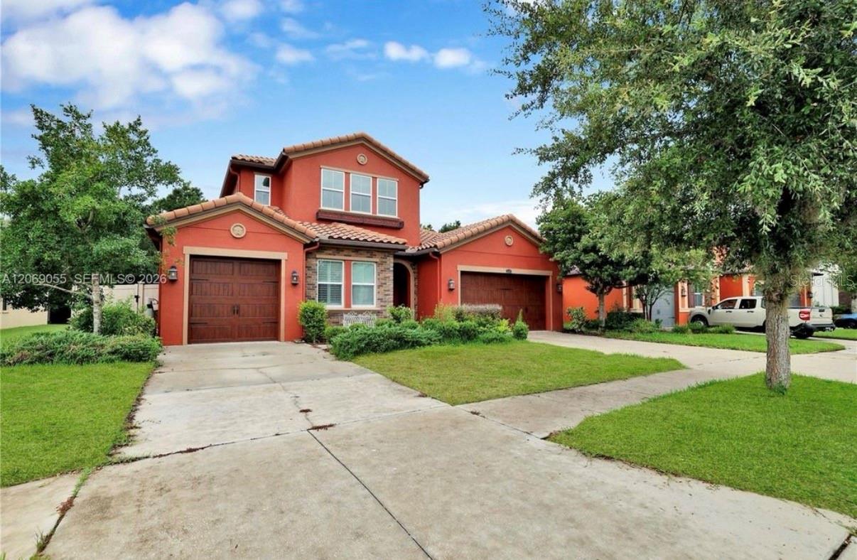 Two-story terracotta house with stone accents, two garage doors, and a wide concrete driveway.