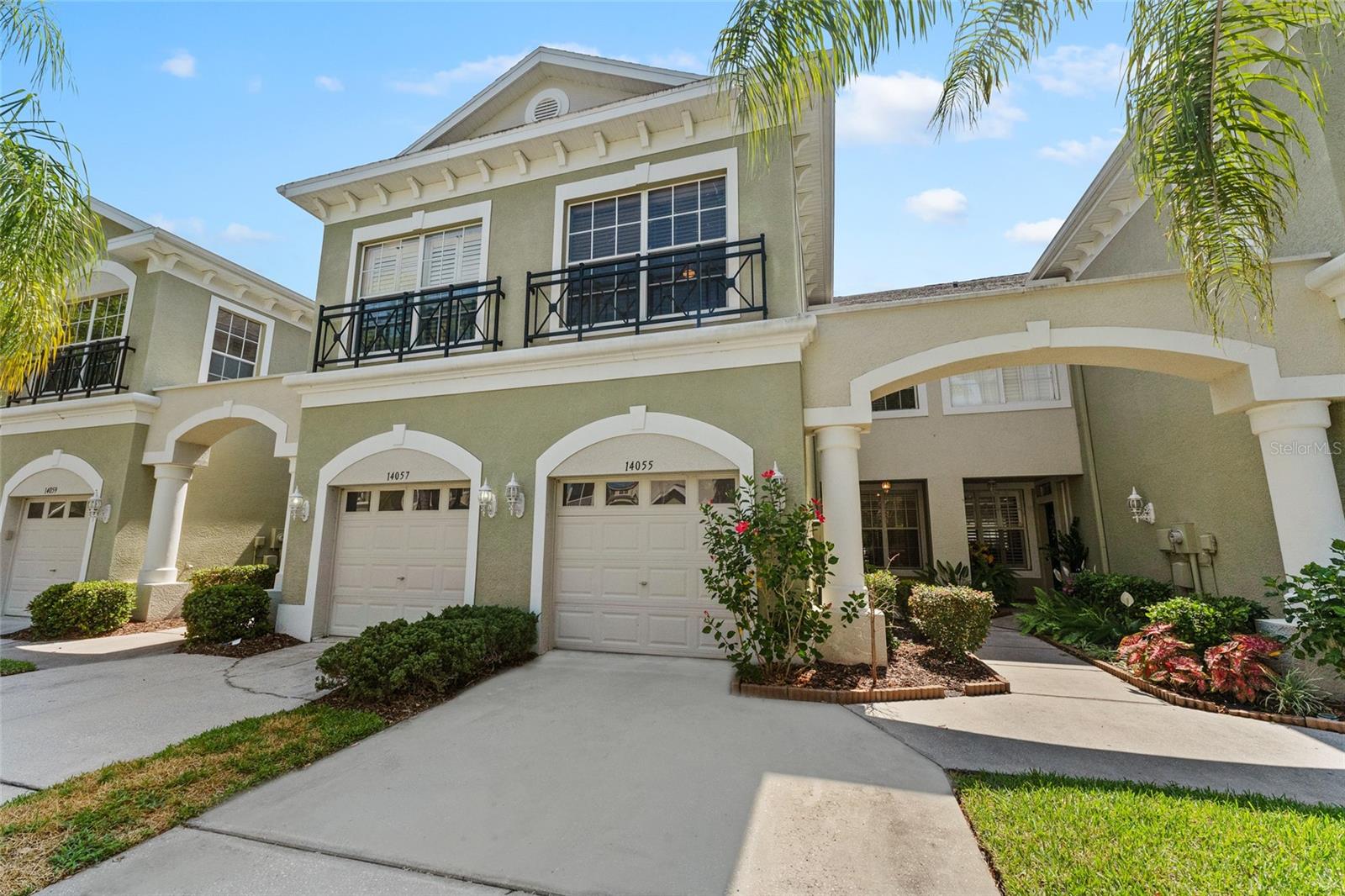 Two-story townhouse marked 14055, with black balcony railings, white trim, and an attached garage.
