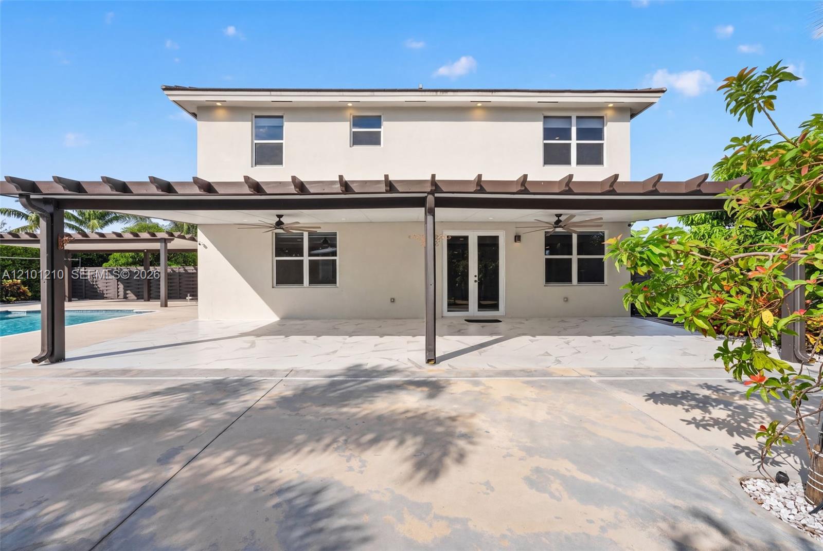 Two-story home with a broad pergola-covered patio and swimming pool visible at the left.