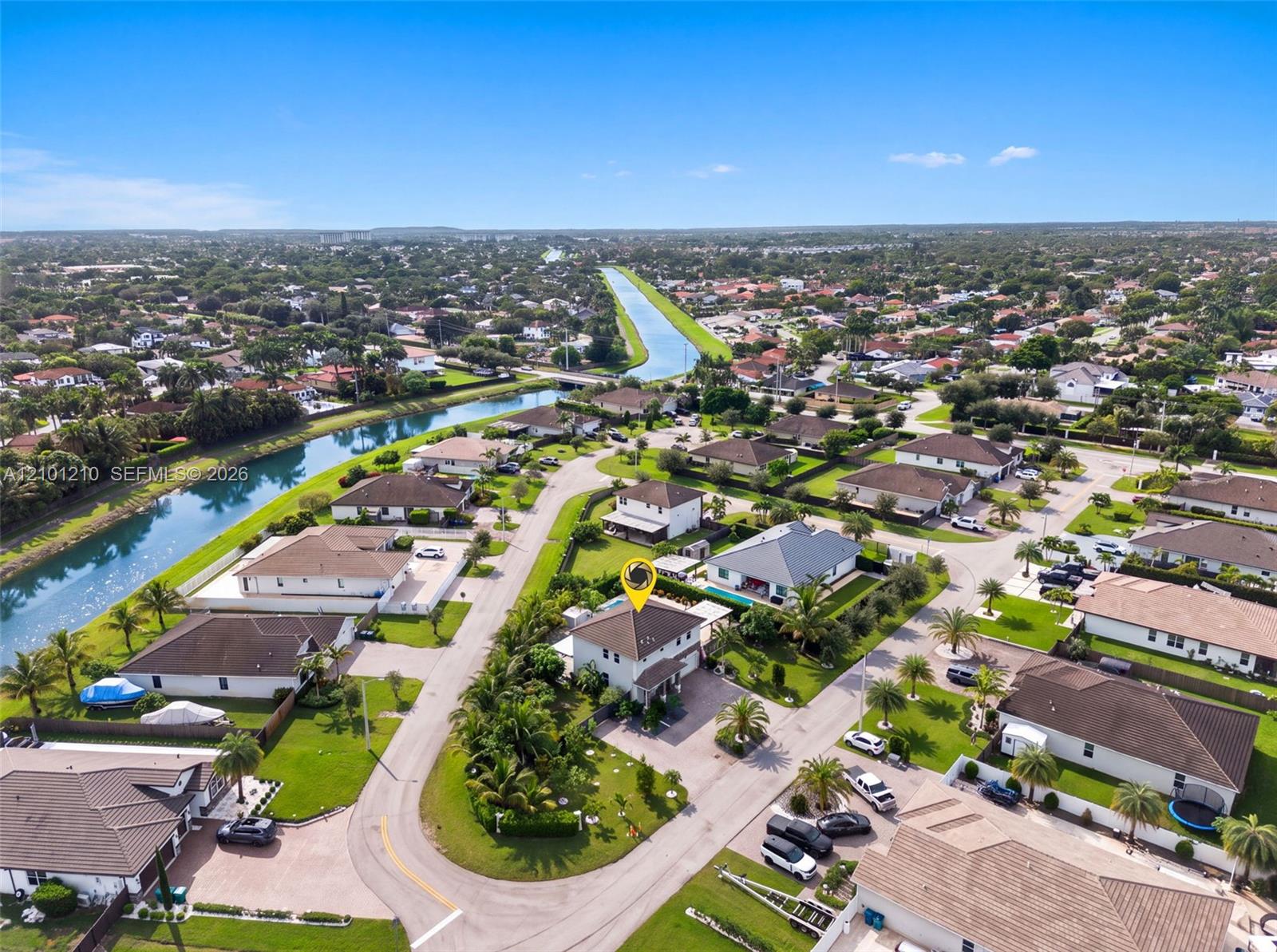 Aerial view of the home marked by a yellow pin, with a canal and neighborhood houses nearby.