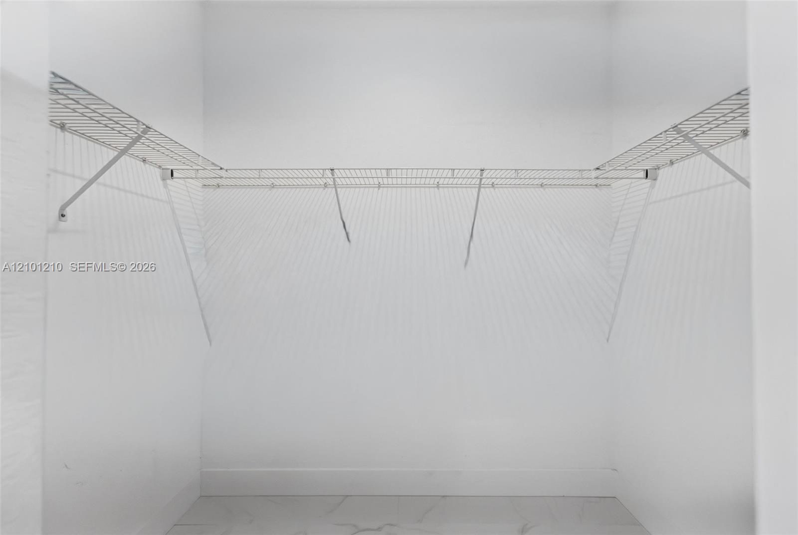Empty walk-in closet with white wire shelving along three walls.