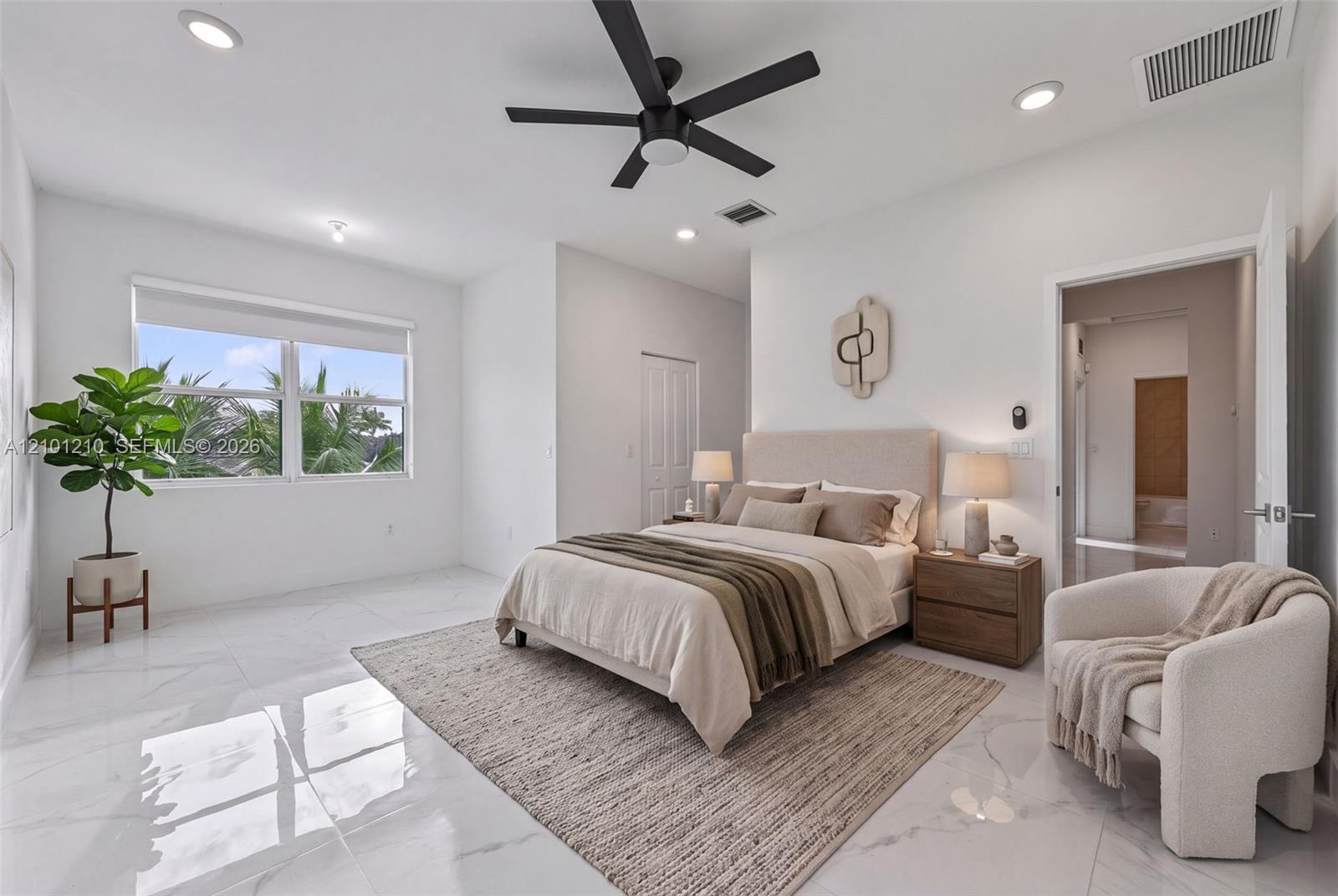 Furnished bedroom with a king bed, glossy tile floors, and a window overlooking palm trees.