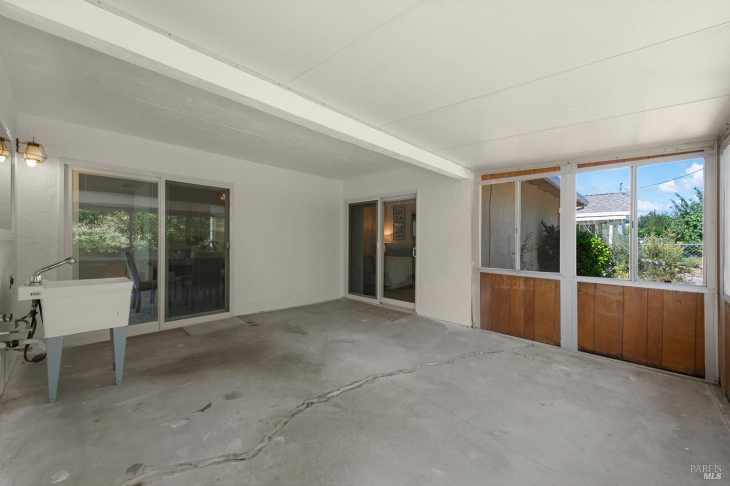 Enclosed patio with a concrete floor, sliding glass doors, and a utility sink.